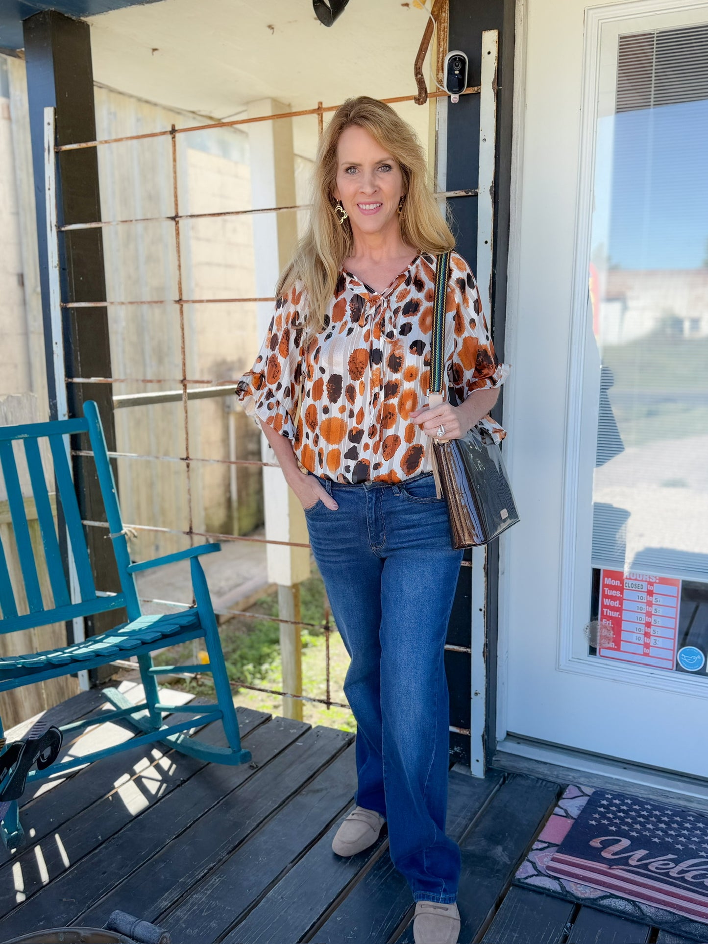 Woman standing on a porch with a blue chair and a white door in the background