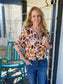 Woman wearing a patterned blouse and jeans on a porch