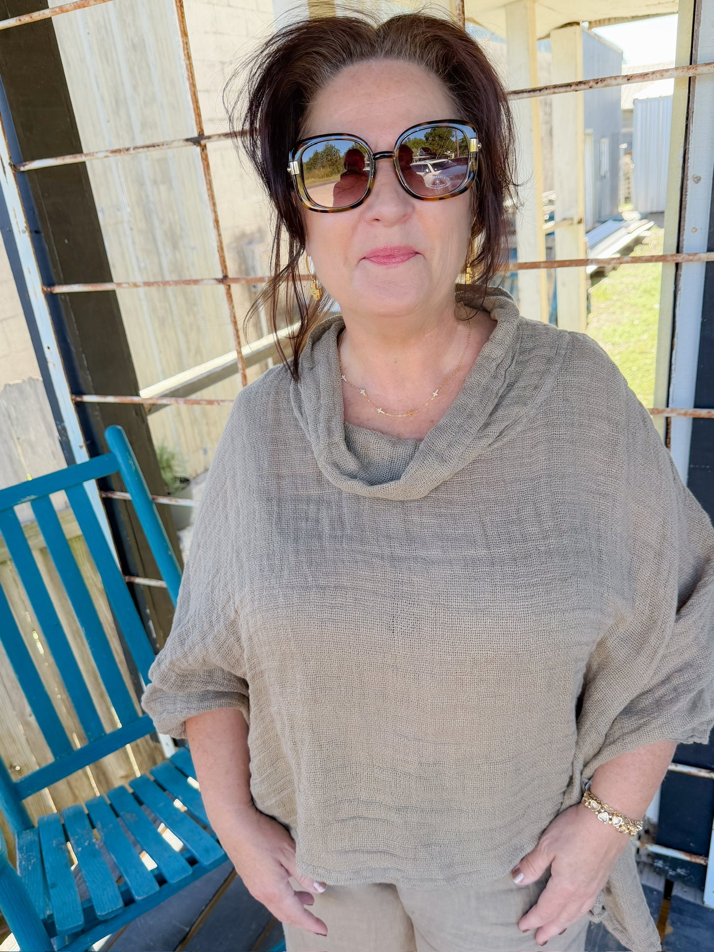 Woman wearing sunglasses and a beige outfit on a porch