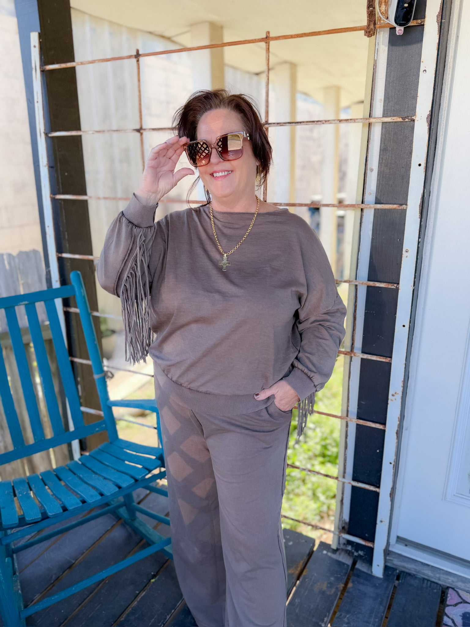 Woman wearing sunglasses and a brown outfit on a porch