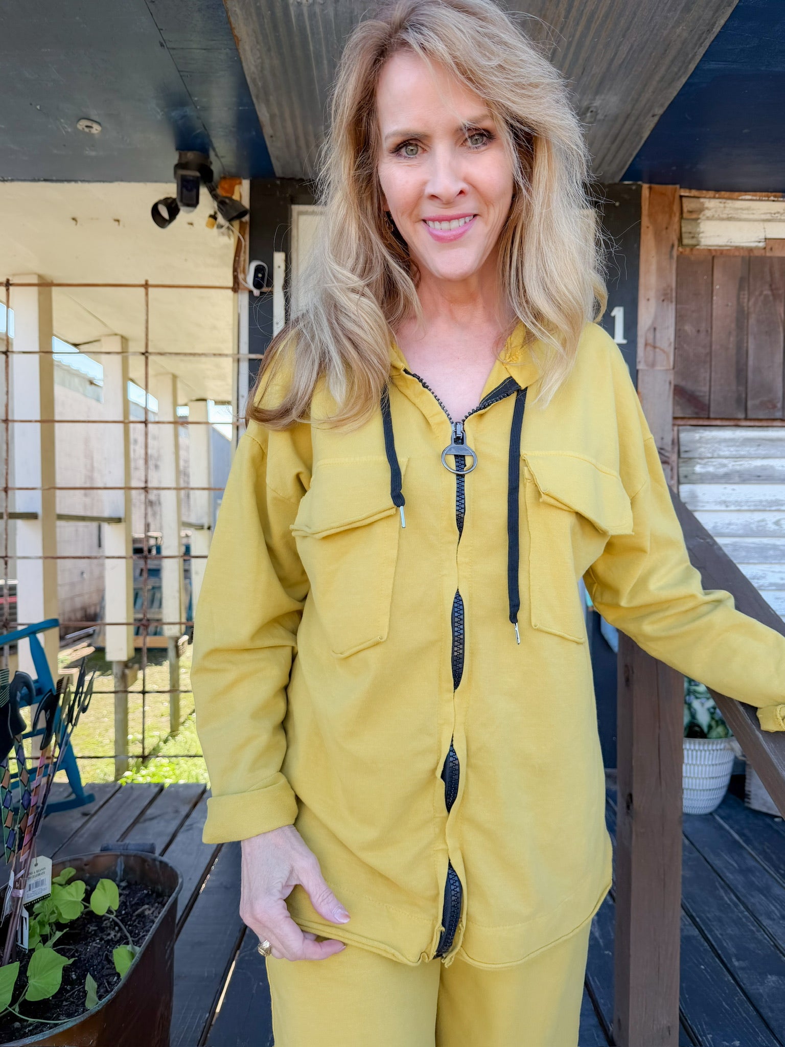 Woman wearing a yellow raincoat standing on a wooden deck.
