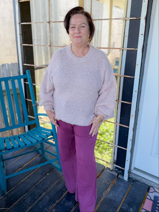 Woman standing on a porch with a blue chair and white door in the background