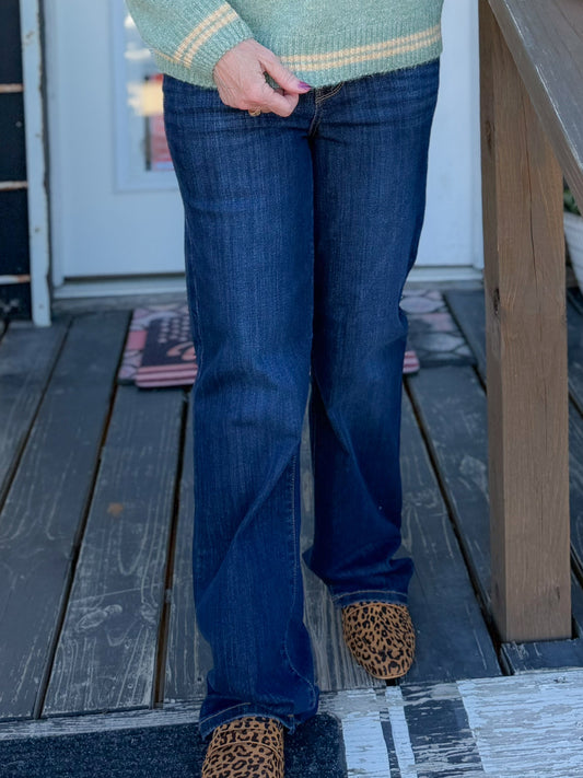 Woman wearing a green sweater with 'See you, Cowboy' text on a wooden porch.