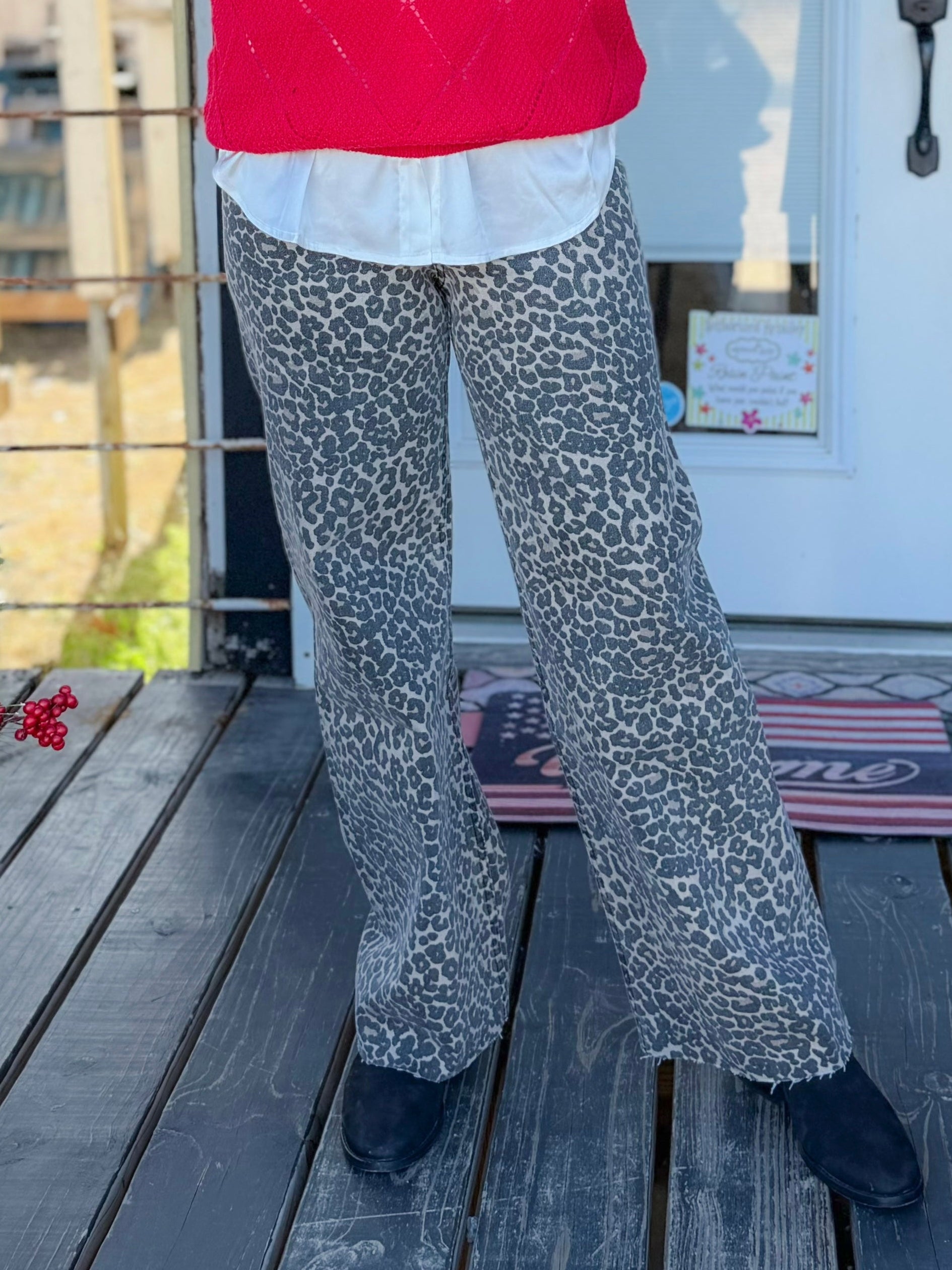 Woman in a red sweater standing on a wooden porch with Christmas decorations.