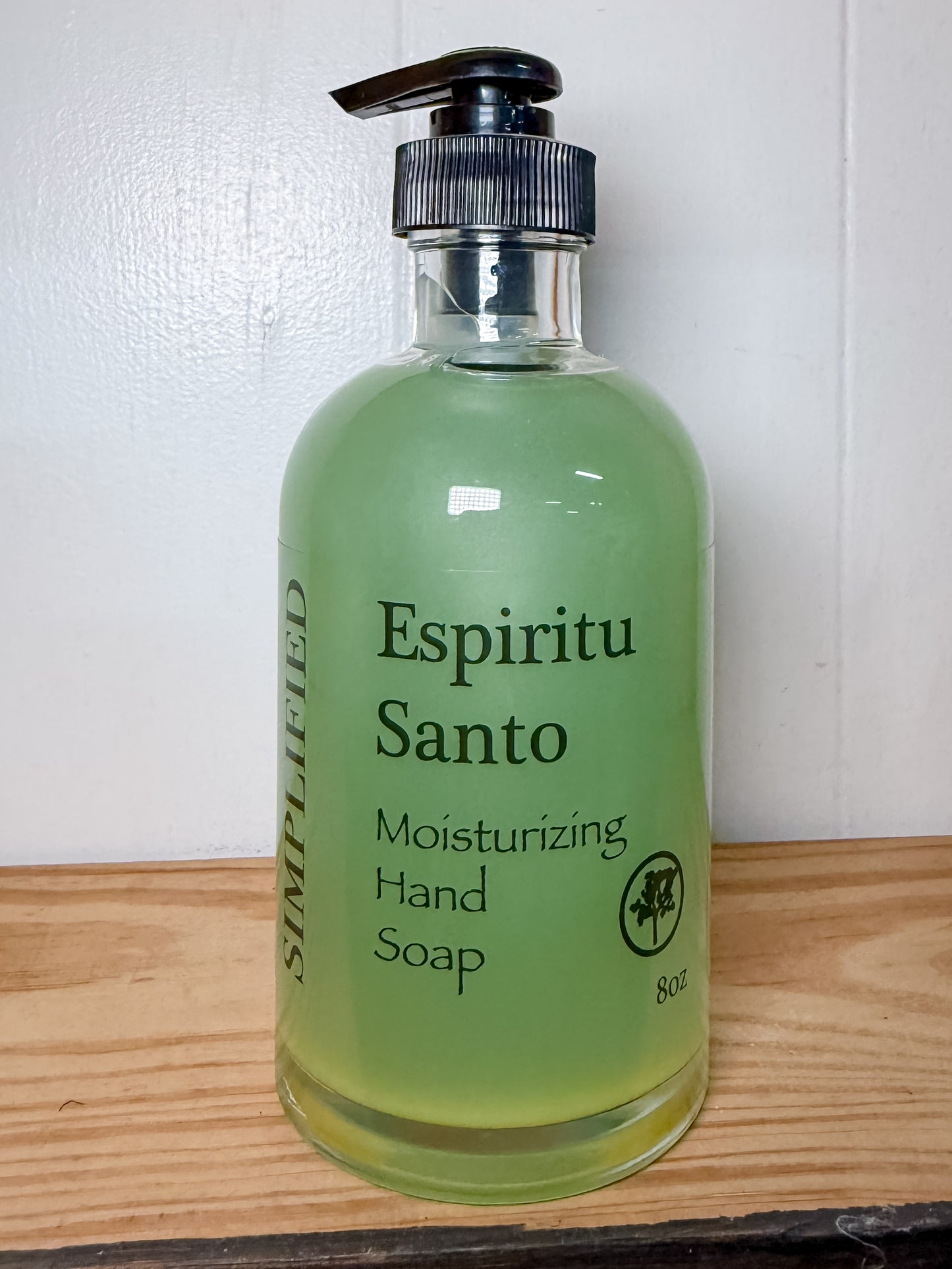 Green bottle of Espiritu Santo moisturizing hand soap on a wooden surface with a white background