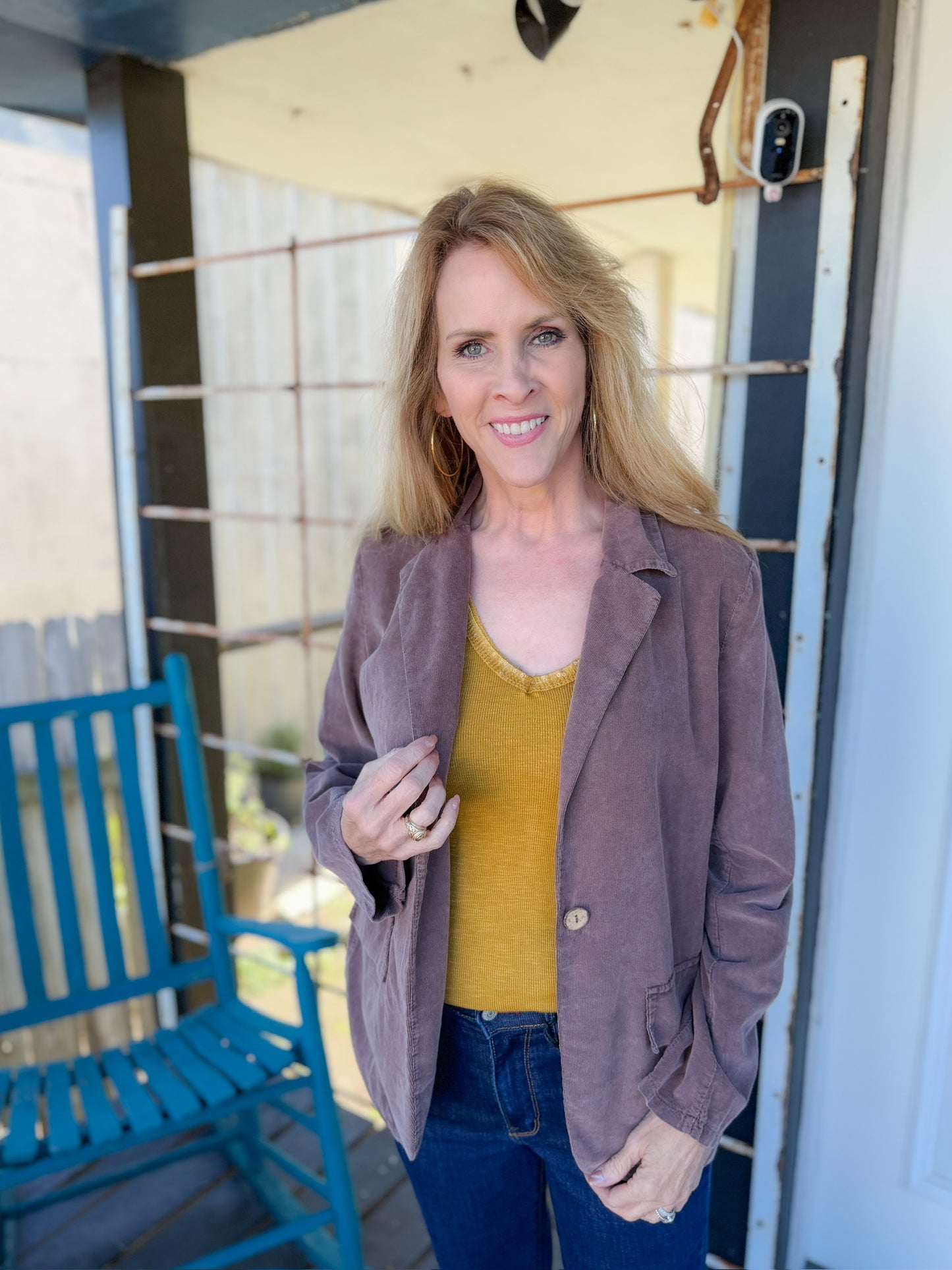 Woman standing on a porch with a blue chair and open door